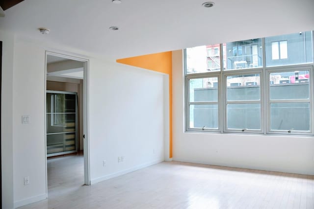 spare room with baseboards and light wood-style floors