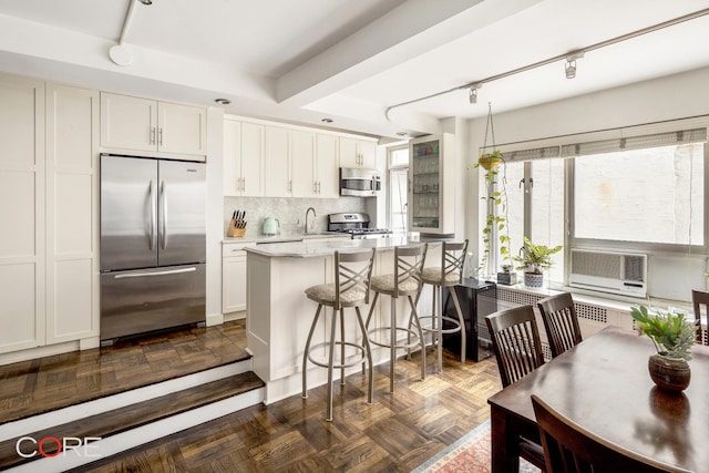 20 E 35th St Unit 2E, New York City, NY 10016 - kitchen featuring white cabinets, light countertops, a kitchen bar, track lighting, and appliances with stainless steel finishes