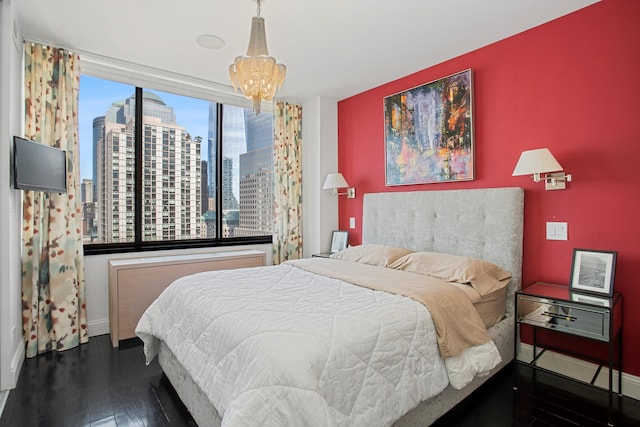 bedroom with a city view, a notable chandelier, wood finished floors, and baseboards