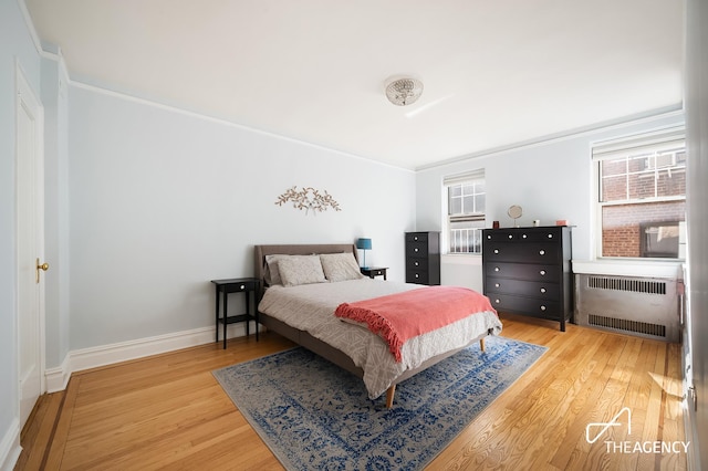 bedroom featuring radiator heating unit, wood finished floors, and baseboards