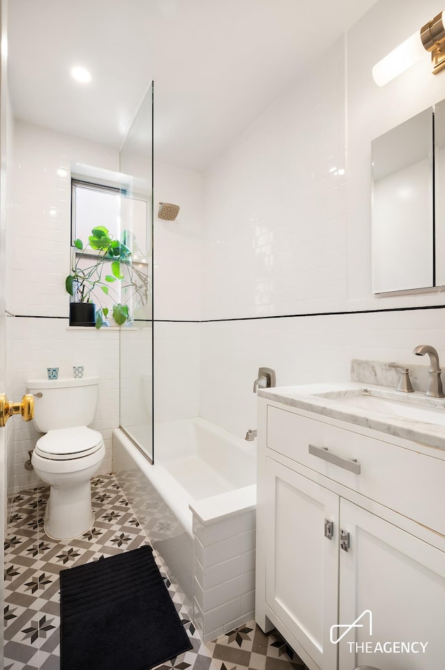 bathroom featuring vanity, tile walls, toilet, and washtub / shower combination