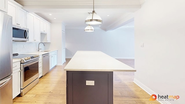 kitchen featuring light wood finished floors, appliances with stainless steel finishes, a center island, light countertops, and a sink