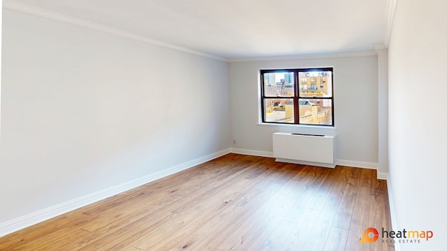 spare room featuring ornamental molding, light wood-type flooring, and baseboards