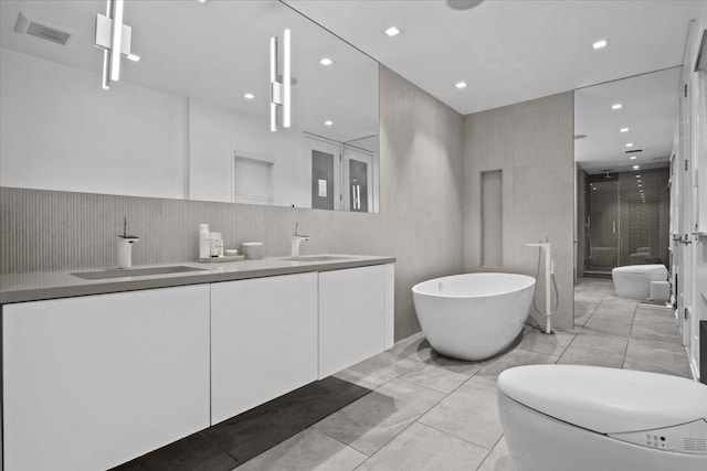 bathroom with visible vents, a sink, a shower stall, and double vanity