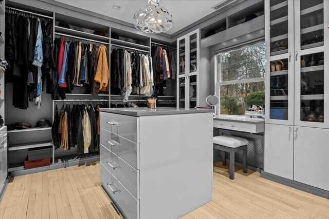 spacious closet featuring wood-type flooring and an inviting chandelier