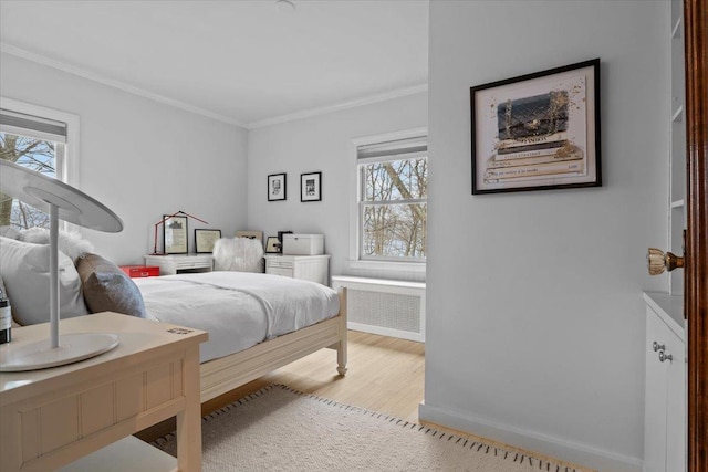 bedroom featuring baseboards, ornamental molding, wood finished floors, and radiator