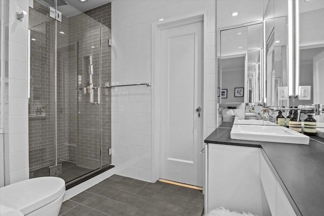 bathroom featuring toilet, a stall shower, vanity, and tile patterned floors