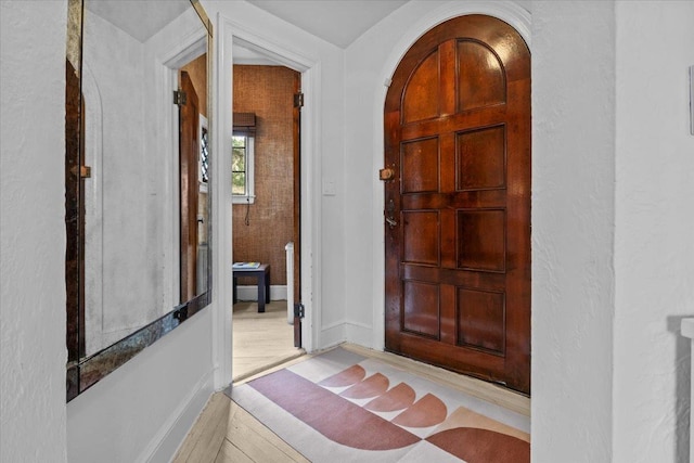 interior space featuring arched walkways, baseboards, and wood finished floors