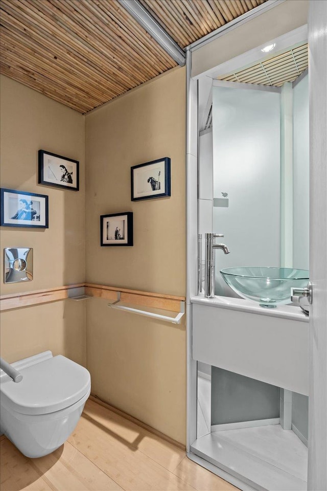 bathroom with toilet, wooden ceiling, and a sink