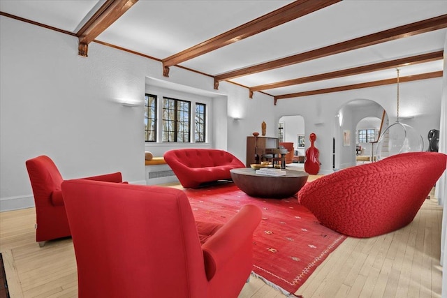 living room featuring arched walkways, wood-type flooring, beam ceiling, and baseboards