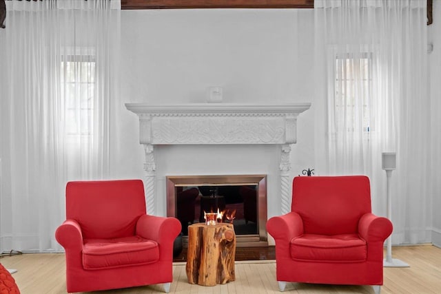 sitting room with a glass covered fireplace and wood finished floors