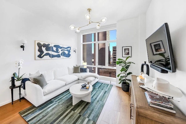 living room with a notable chandelier, baseboards, and wood finished floors