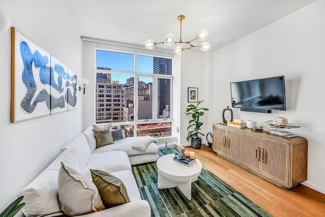 living area with a chandelier, light wood-style flooring, and baseboards