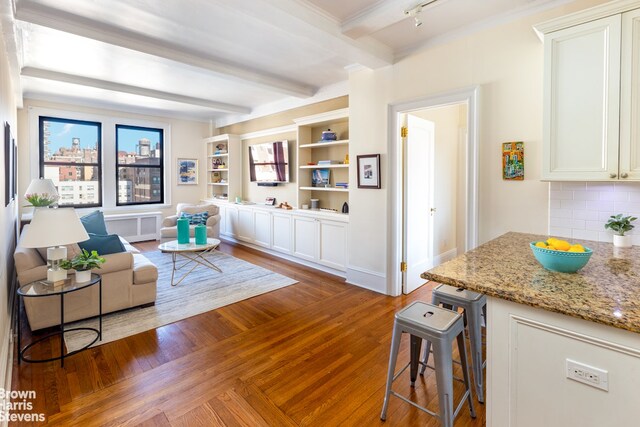 sitting room featuring radiator, beamed ceiling, and wood finished floors