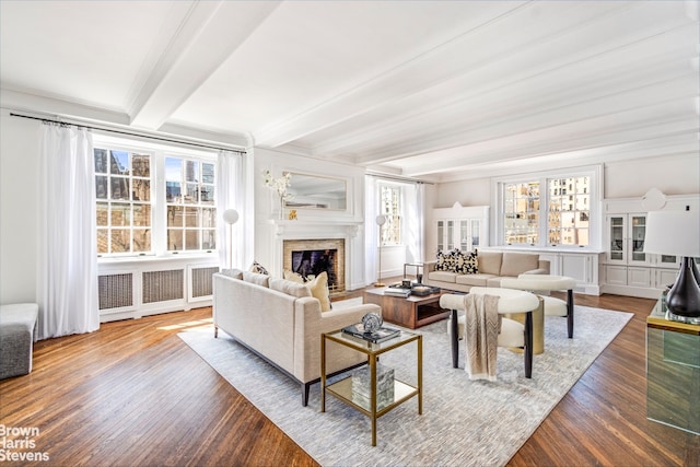 living room with a fireplace with flush hearth, plenty of natural light, beamed ceiling, and wood finished floors