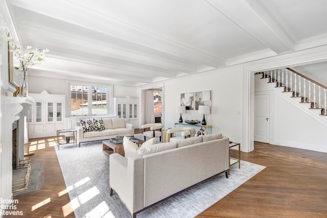 living area with a premium fireplace, stairway, beamed ceiling, dark wood finished floors, and crown molding