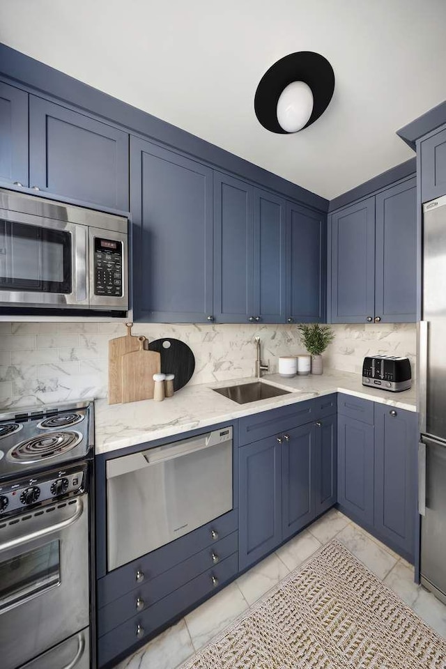 kitchen featuring light stone counters, marble finish floor, blue cabinetry, tasteful backsplash, and appliances with stainless steel finishes