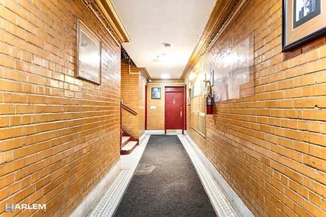 corridor with brick wall, ornamental molding, and baseboards