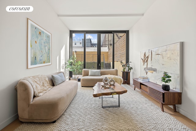 living room with wood finished floors, baseboards, visible vents, and expansive windows