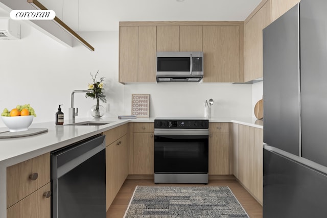 kitchen with a sink, appliances with stainless steel finishes, light brown cabinets, and light countertops