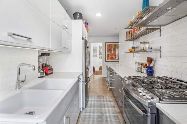 kitchen featuring stainless steel appliances, light countertops, a sink, and modern cabinets