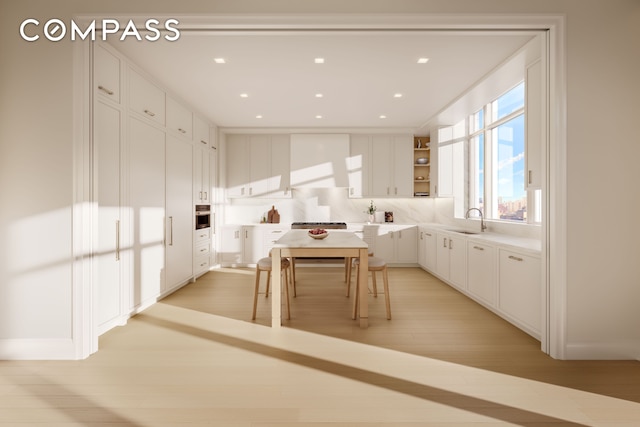 kitchen with open shelves, light wood finished floors, a sink, and white cabinetry