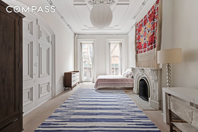 bedroom featuring light wood-style flooring, crown molding, and a tray ceiling