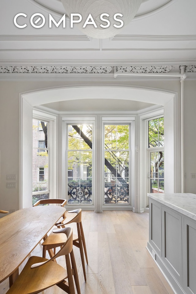 dining area featuring light wood-style flooring, a healthy amount of sunlight, and ornamental molding