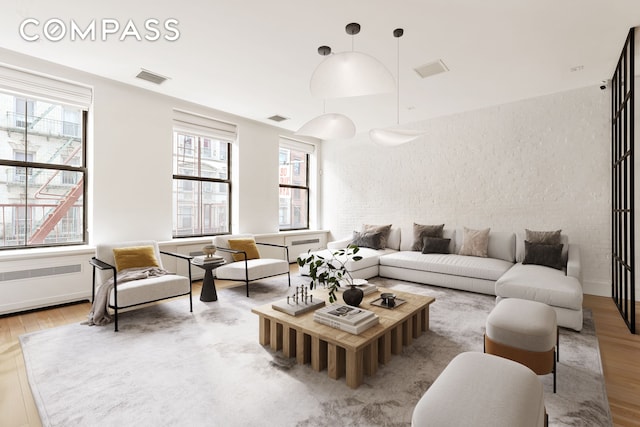 living room with a wealth of natural light, visible vents, and wood finished floors