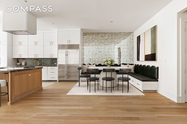 kitchen featuring white cabinetry, dark countertops, light wood-style floors, and stainless steel built in fridge