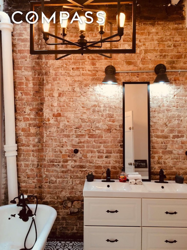 bathroom featuring vanity, a freestanding tub, and brick wall