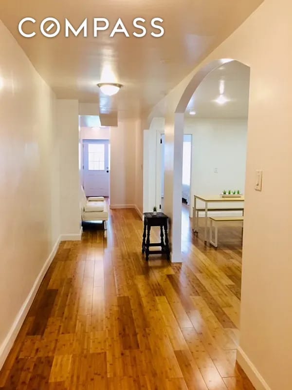 hall featuring hardwood / wood-style floors, baseboards, and arched walkways