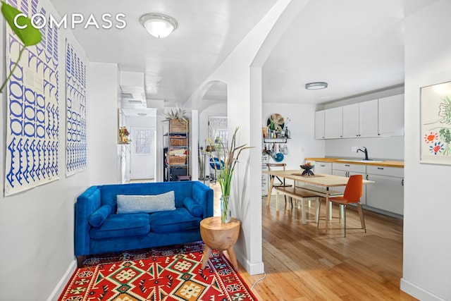 living room featuring light wood-style flooring, baseboards, and arched walkways