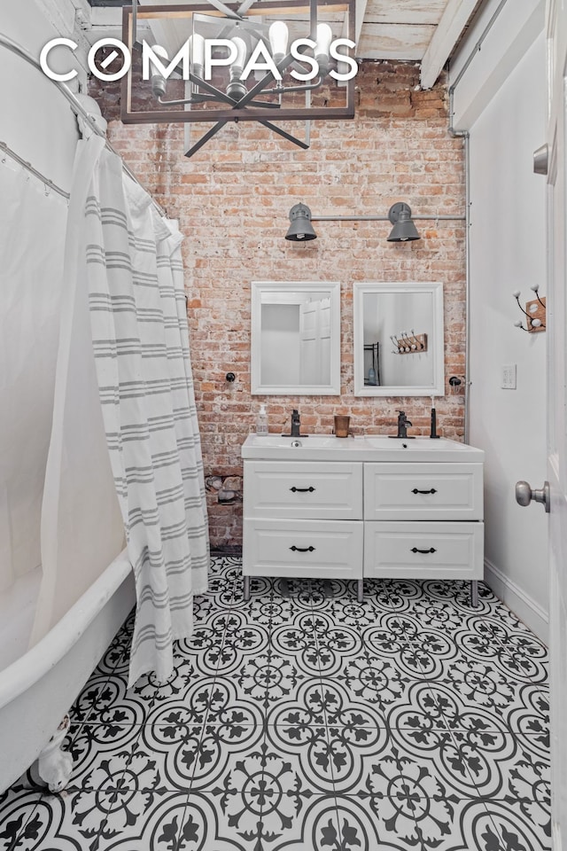 bathroom featuring tile patterned flooring, a notable chandelier, vanity, and brick wall