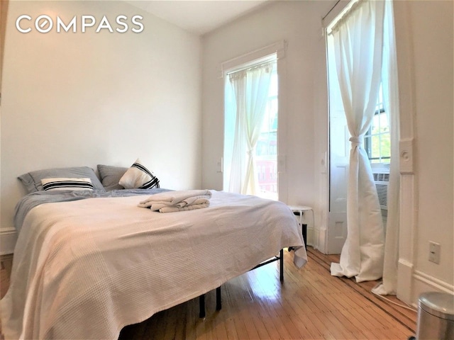 bedroom with multiple windows and light wood-type flooring