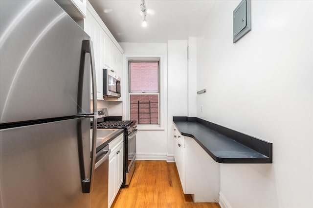 680 W 204th St Unit 3-F, New York City, NY 10034 - kitchen with stainless steel appliances, dark countertops, white cabinets, and light wood-style flooring