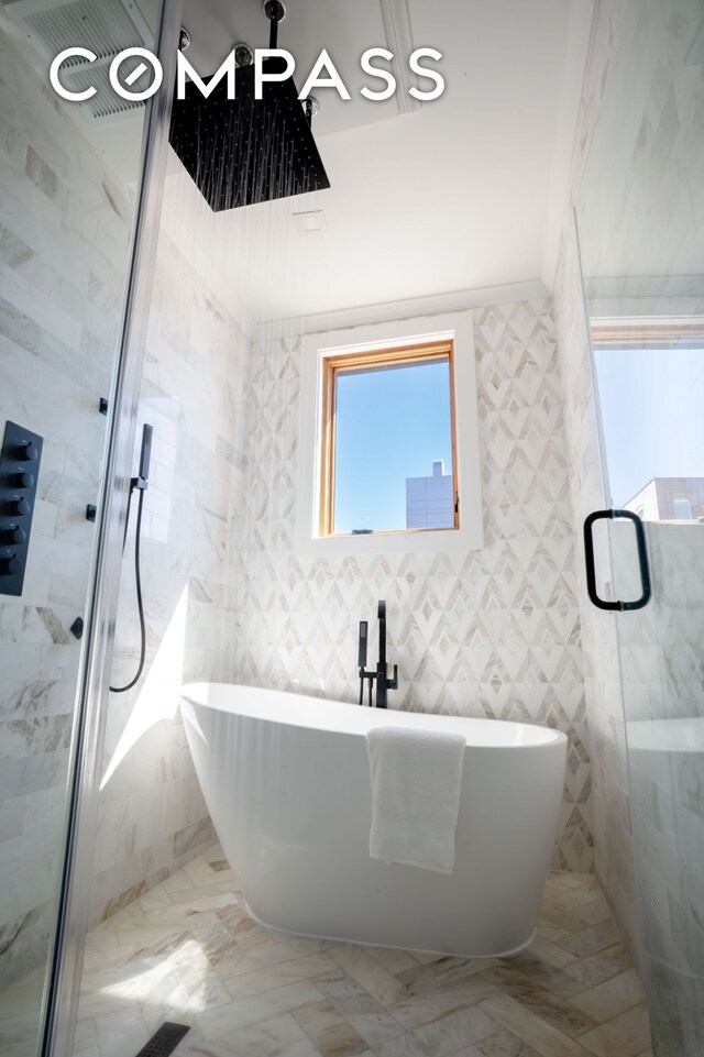 bathroom featuring a stall shower and a freestanding bath