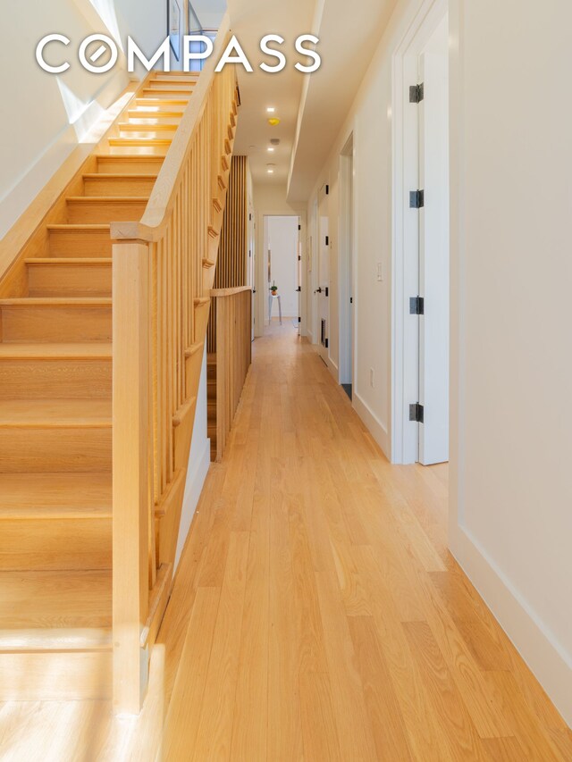 hallway with stairs, baseboards, and wood finished floors