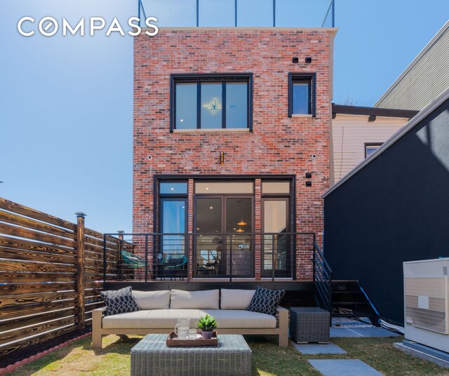 back of property featuring brick siding, outdoor lounge area, and fence