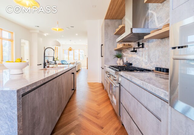 kitchen with modern cabinets, appliances with stainless steel finishes, wall chimney range hood, open shelves, and a sink