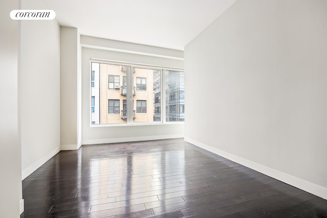 empty room featuring visible vents, baseboards, and dark wood-style floors