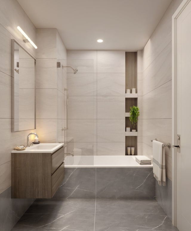 full bath featuring marble finish floor, tiled shower / bath combo, vanity, and tile walls