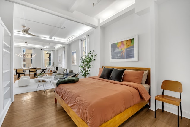 bedroom with beam ceiling, a chandelier, and wood finished floors