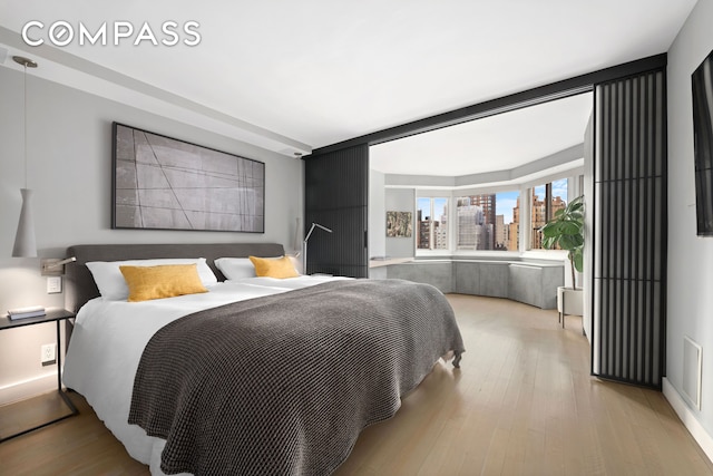 301 E 78th St Unit 16Ef, New York City, NY 10075 - bedroom with light wood-type flooring and a skyline view