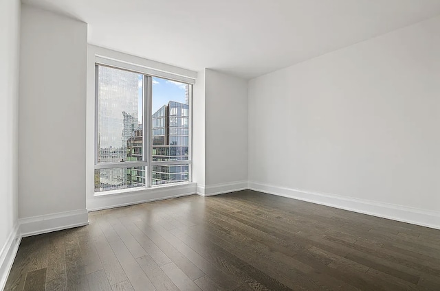 unfurnished room featuring dark wood-type flooring and baseboards