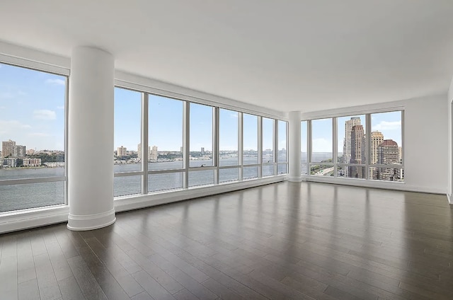 unfurnished sunroom featuring a view of city, a water view, and ornate columns