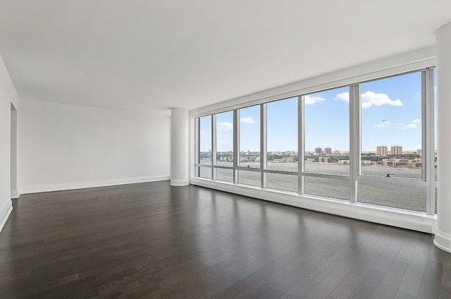 empty room featuring a view of city, baseboards, and dark wood-type flooring