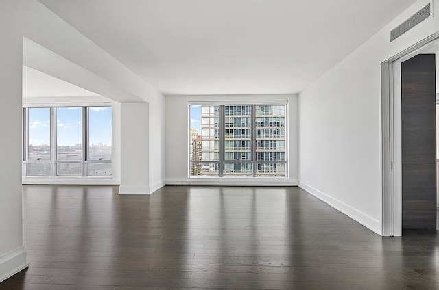 unfurnished room featuring baseboards, visible vents, and dark wood finished floors