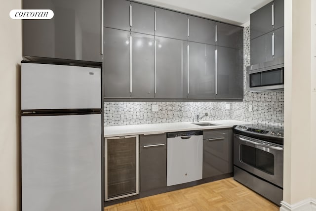 kitchen with stainless steel appliances, decorative backsplash, a sink, and gray cabinetry