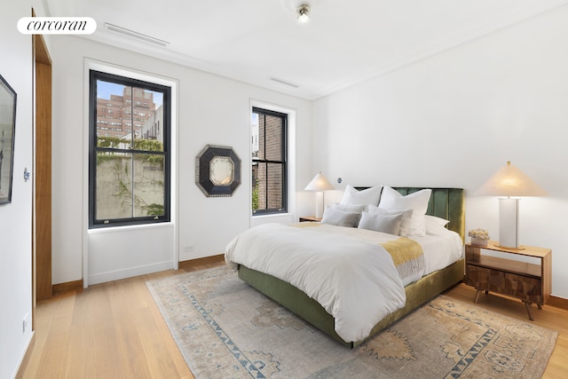 bedroom with visible vents, baseboards, and wood finished floors